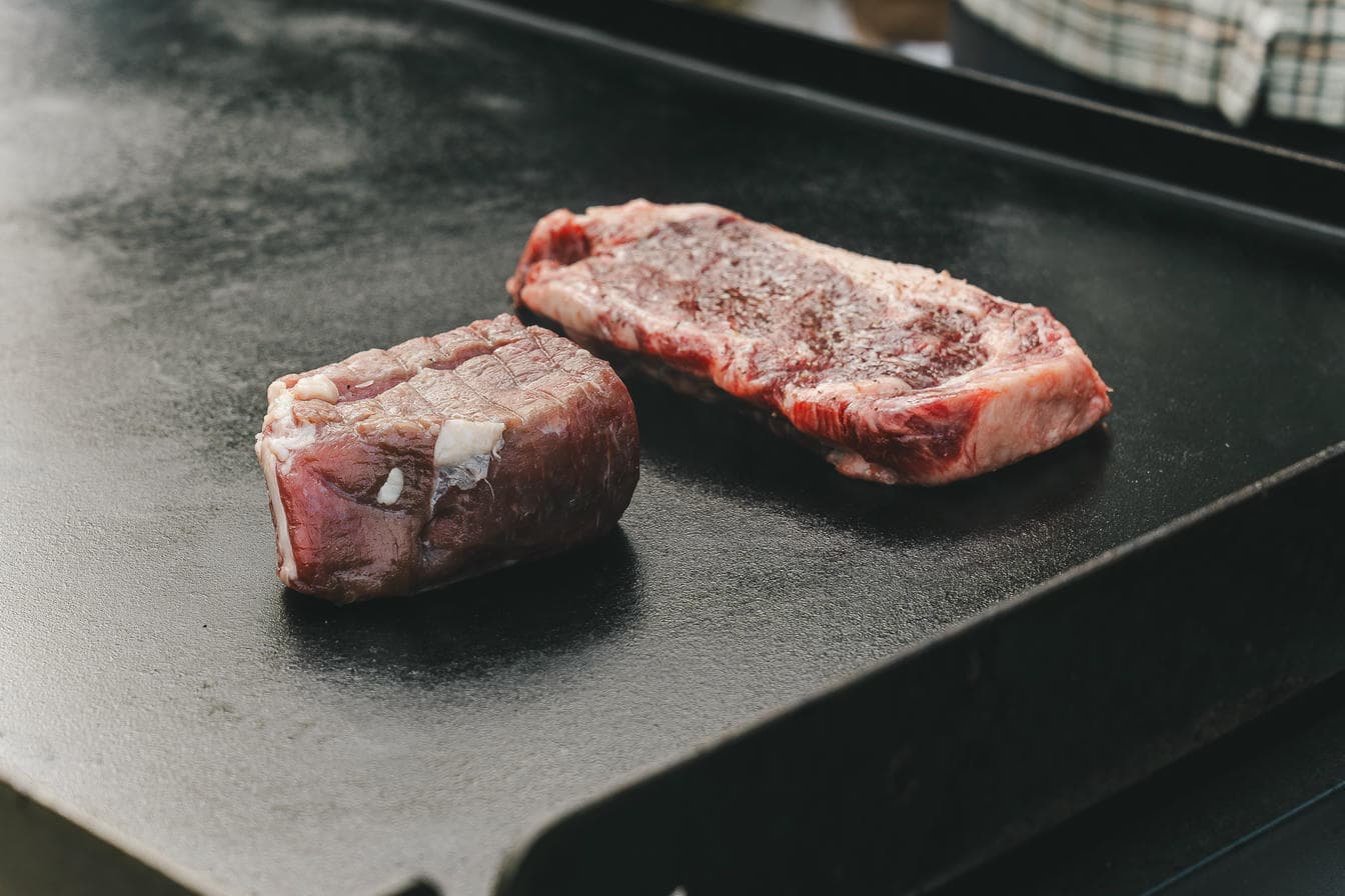 Two dry aged beef steaks on a black griddle